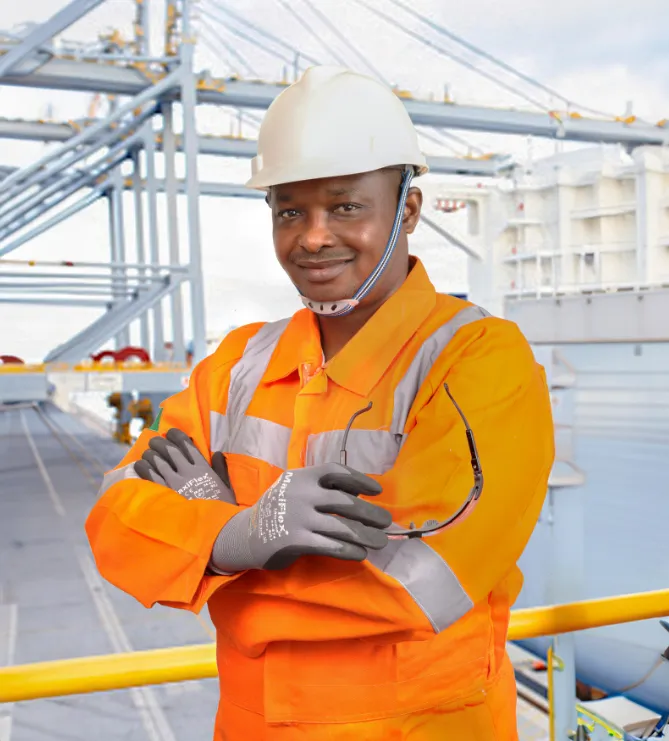 Worker at Ind-Swift manufacturing facility wearing helmet, gloves, safety goggles, and protective yellow uniform as part of EHS compliance.